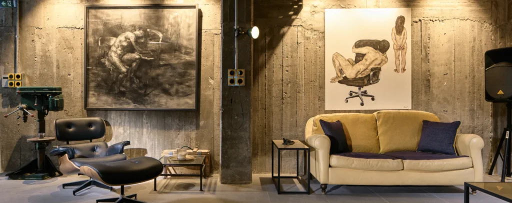 Apart Club House lounge in Athens: concrete walls, large artworks, cream sofa and leather lounge chair